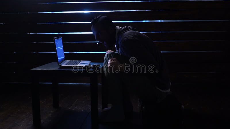 Den komiska roliga en hacker begår en cyberattack med en bärbar dator och ett vapen i hans händer