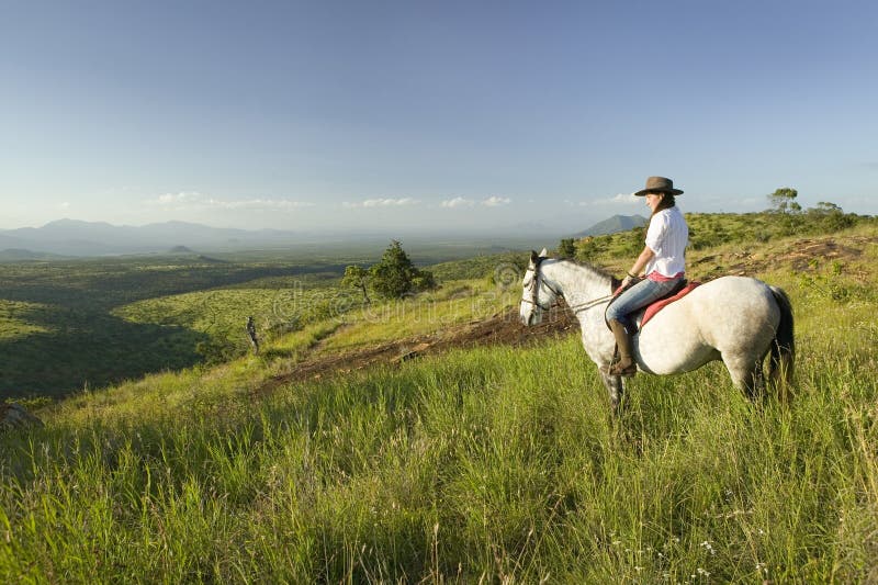 Den kvinnliga den hästryggryttaren och hästen rider att förbise Lewa djurlivnaturvård i norr Kenya, Afrika royaltyfri fotografi Den kvinnliga den hästryggryttaren och hästen rider att förbise Lewa djurlivnaturvård i norr Kenya, Afrika royaltyfri fotografi