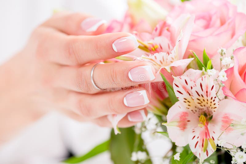 Den kvinnliga handen med rörande blomma för härlig manikyr blommar royaltyfri fotografi Den kvinnliga handen med rörande blomma för härlig manikyr blommar royaltyfri fotografi