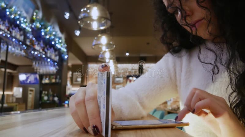 Den ledsna härliga flickan med lockigt hår i en restaurang shoppar direktanslutet