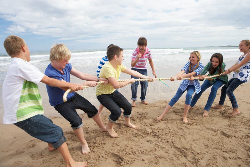 Teenagers playing tug of war on beach. Teenagers playing tug of war on beach