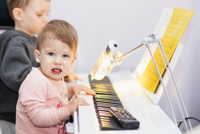Den lilla flickan tycker om att spela den elektriska pianosyntet för fet arkivfoto Den lilla flickan tycker om att spela den elektriska pianosyntet för fet arkivfoto