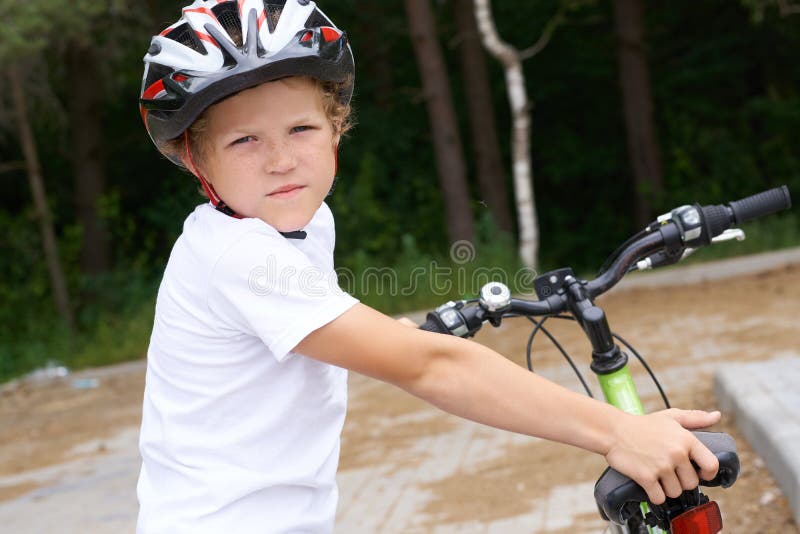Den lilla kaukasiska pojken i hjälmen lutar sig mot att cykla för kameran Teenager redo att åka arkivbilder