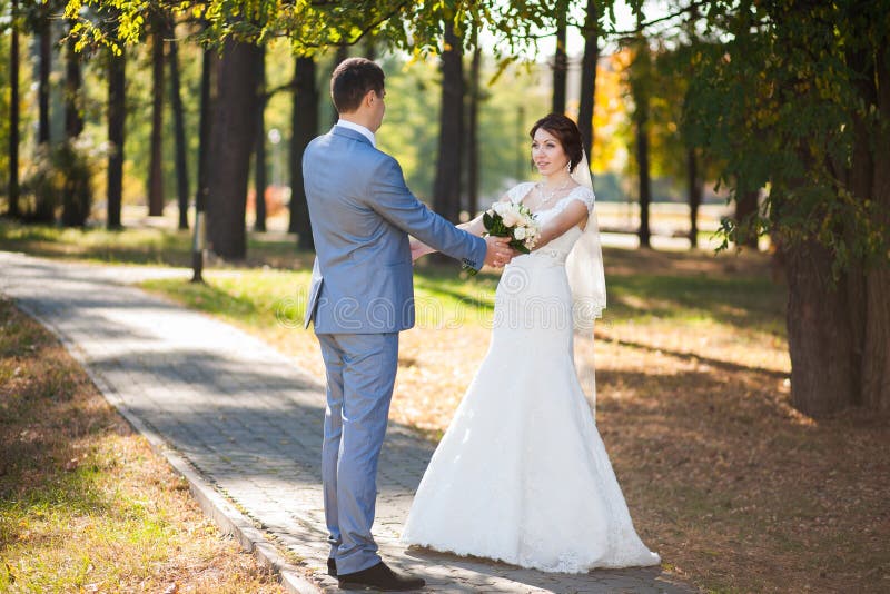Den lyckliga bruden, brudgumdans i gräsplan parkerar och att kyssa och att le som skrattar vänner i bröllopdag förbunden lyckligt