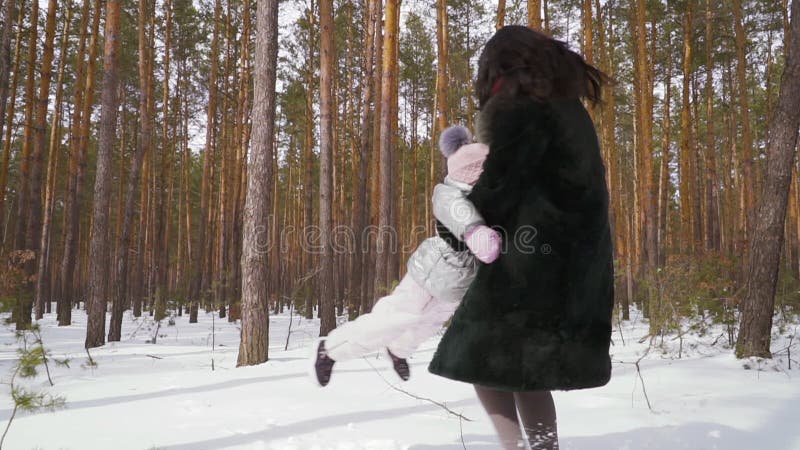 Den lyckliga familjen har gyckel tillsammans i vinterskogen som är slowmotion