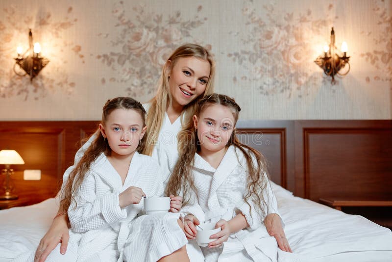Den lyckliga familjen, modern och döttrarna kopplar samman, sitter och kopplar av på a royaltyfri bild Den lyckliga familjen, modern och döttrarna kopplar samman, sitter och kopplar av på a royaltyfri bild