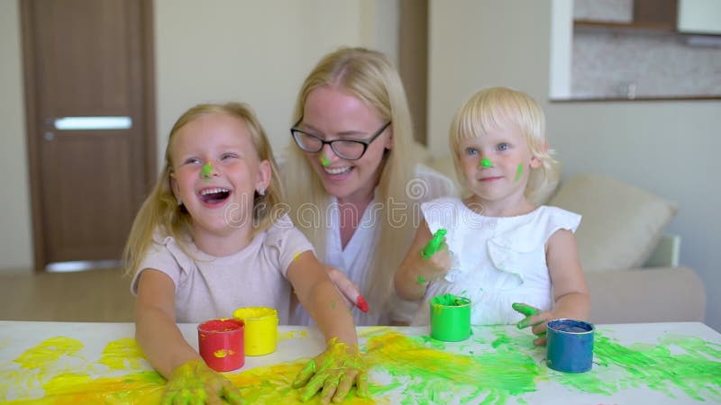 Den lyckliga familjen målar färger Den lyckliga familjen målar färger Modern och dottern som har gyckel och, målar sig ` s på fra