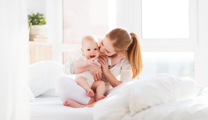 Den lyckliga familjmodern med behandla som ett barn att spela och kramar i säng royaltyfria foton Den lyckliga familjmodern med behandla som ett barn att spela och kramar i säng royaltyfria foton