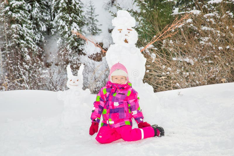 Den lyckliga flickan för det härliga barnet som plaing med en snögubbe på snöig vinter, går arkivbild Den lyckliga flickan för det härliga barnet som plaing med en snögubbe på snöig vinter, går arkivbild