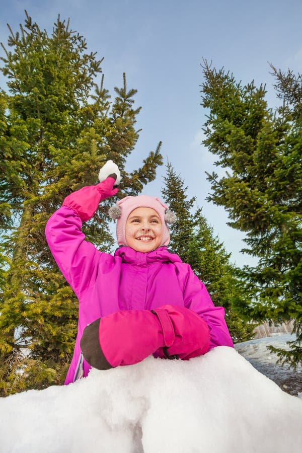 Den lyckliga flickan som är klar att kasta, kastar snöboll under leken royaltyfri fotografi Den lyckliga flickan som är klar att kasta, kastar snöboll under leken royaltyfri fotografi