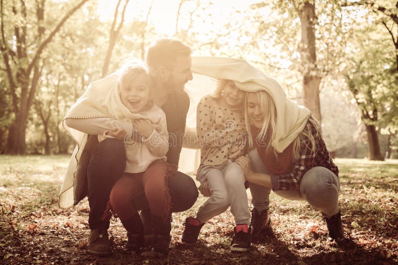 Den lyckliga le familjen som in spelar, parkerar med filten arkivbild Den lyckliga le familjen som in spelar, parkerar med filten arkivbild
