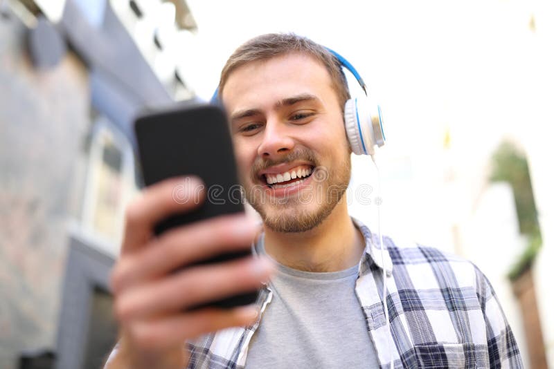 Den lyckliga mannen lyssnar till musiken som går i gatan royaltyfri bild Den lyckliga mannen lyssnar till musiken som går i gatan royaltyfri bild