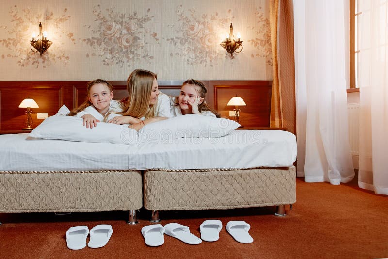 Den lyckliga modern och barn kopplar samman att vila i säng royaltyfri bild Den lyckliga modern och barn kopplar samman att vila i säng royaltyfri bild