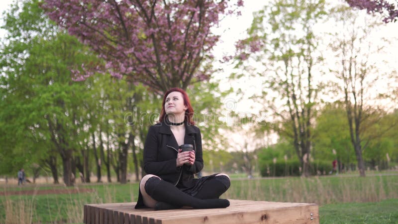 Den lyckliga unga loppdansarekvinnan som tycker om fri tid i en sakura k? rsb? rblomning, parkerar - den Caucasian vita r? dh? rig ma lager videofilmer