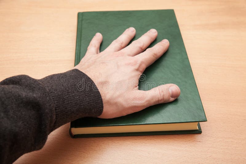 Den manliga handen som lägger på boken, svär begrepp arkivfoton Den manliga handen som lägger på boken, svär begrepp arkivfoton