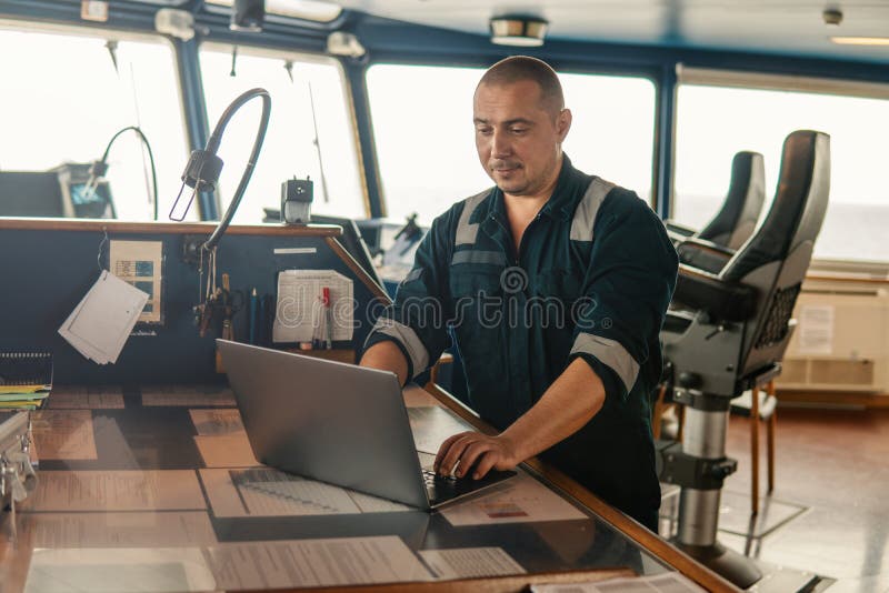 Den marin- navigations- tjänstemannen använder bärbara datorn eller anteckningsboken på havet royaltyfria foton Den marin- navigations- tjänstemannen använder bärbara datorn eller anteckningsboken på havet royaltyfria foton