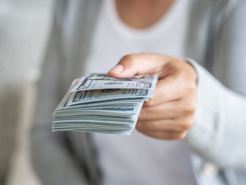 Den mjuka fokusen på kvinna räcker förslag av pengar oss dollarräkningar till dig arkivbilder Den mjuka fokusen på kvinna räcker förslag av pengar oss dollarräkningar till dig arkivbilder
