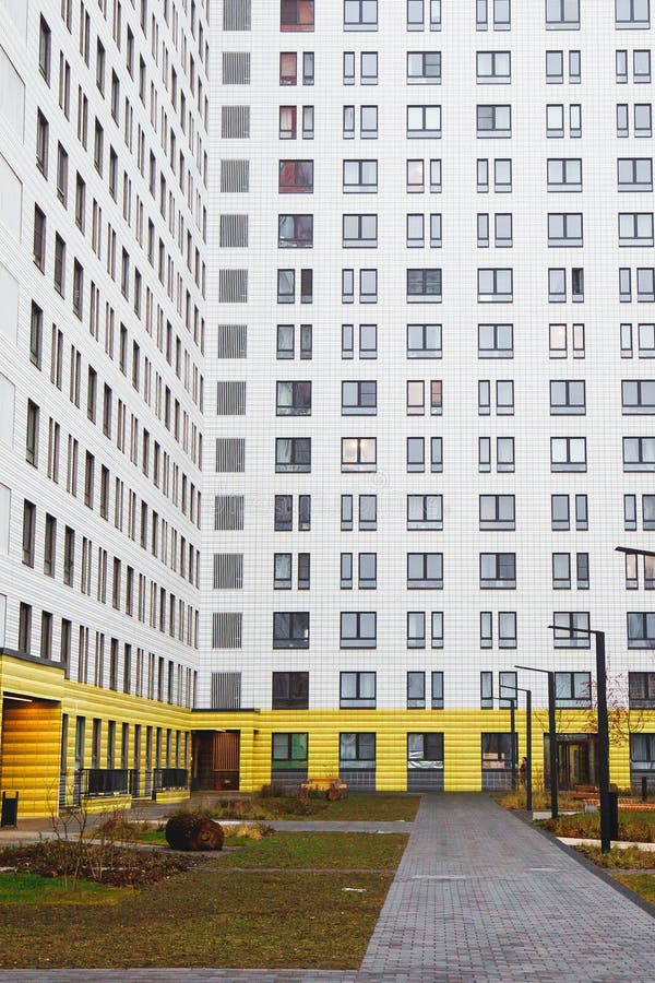 Den moderna gården i en lägenhetshus i staden, huset är gulvitt, vägar, bänkar och ljus royaltyfria bilder
