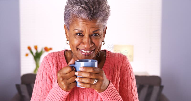 Den mogna svarta kvinnan som ler med kaffe, rånar