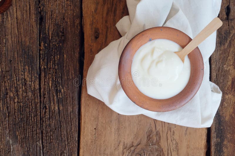 Den naturliga hemlagade vanliga organiska yoghurten blandade med den nya vita bunken för bärfrukt och träskeden på trätexturbakgr royaltyfria bilder Den naturliga hemlagade vanliga organiska yoghurten blandade med den nya vita bunken för bärfrukt och träskeden på trätexturbakgr royaltyfria bilder