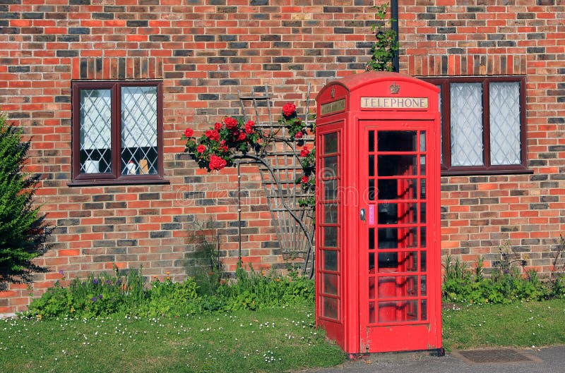 Den nostalgiska telefonasken av väggen för röd tegelsten med vandraren steg framme royaltyfri foto Den nostalgiska telefonasken av väggen för röd tegelsten med vandraren steg framme royaltyfri foto