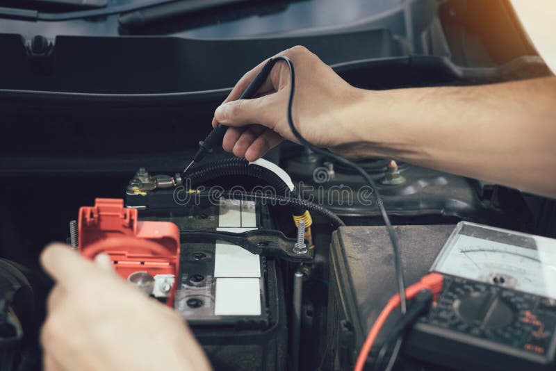 Den nära övre bilmekanikern använder bilbatterimetern för att mäta olika värden och för att analysera det arkivfoto