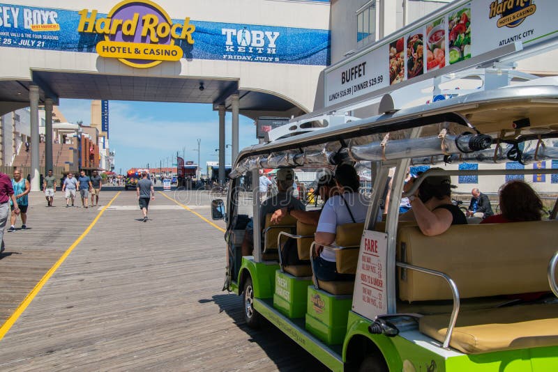 Den nära övre sikten av en grön spårvagnbil som fylls med turister som rider på den Atlantic City strandpromenaden nära det hårt, arkivbild Den nära övre sikten av en grön spårvagnbil som fylls med turister som rider på den Atlantic City strandpromenaden nära det hårt, arkivbild