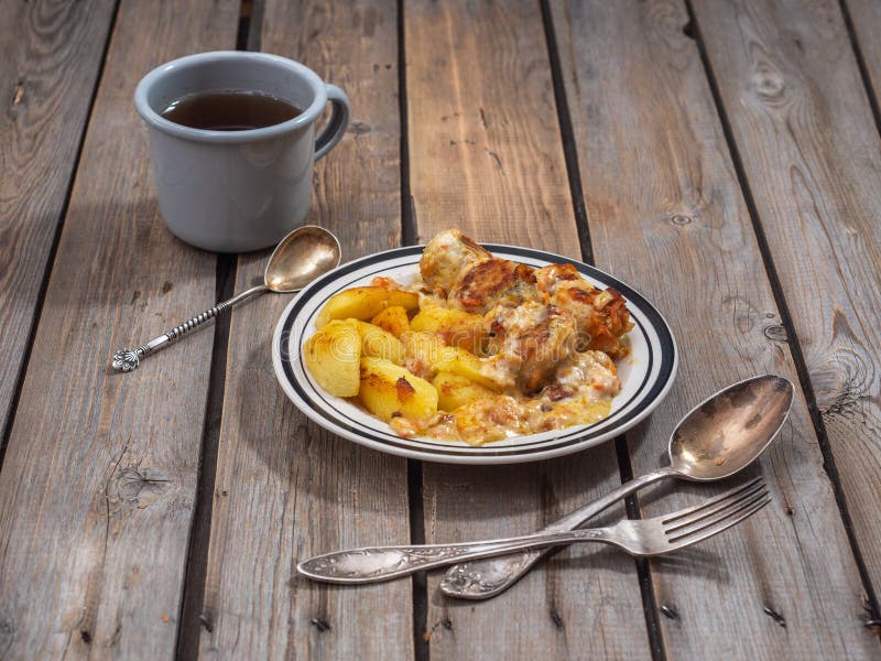 Den näringsrika frukosten av köttbullar och stekte potatisar, snittet in i stora skivor, te i en aluminiumgrå färg rånar för best arkivbild Den näringsrika frukosten av köttbullar och stekte potatisar, snittet in i stora skivor, te i en aluminiumgrå färg rånar för best arkivbild