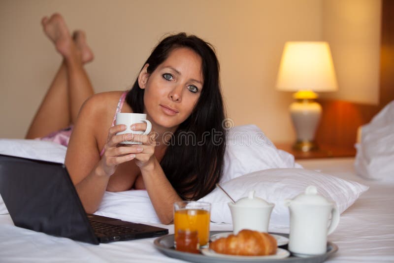 Den nätta kvinnan har frukosten i en hotellsäng royaltyfri foto Den nätta kvinnan har frukosten i en hotellsäng royaltyfri foto