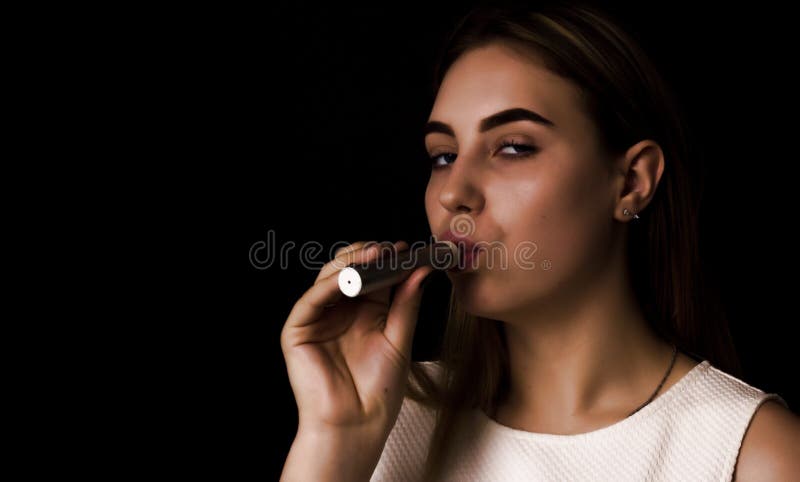 Den nätta unga flickan använder den elektroniska cigaretten royaltyfri bild Den nätta unga flickan använder den elektroniska cigaretten royaltyfri bild