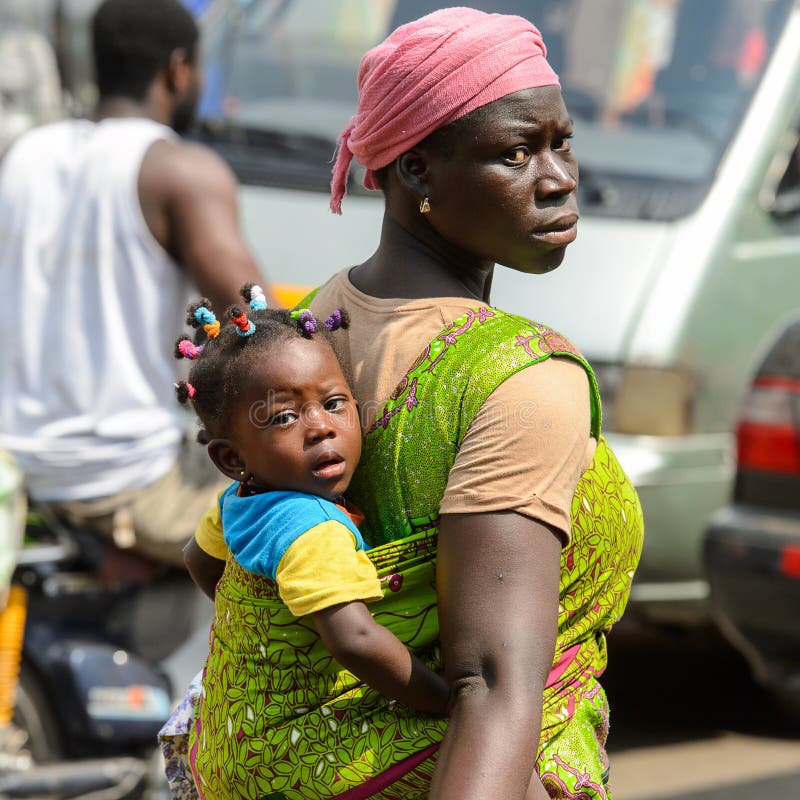 Den oidentifierade ghananska kvinnan bär en behandla som ett barn på den Kumasi marknaden royaltyfri bild