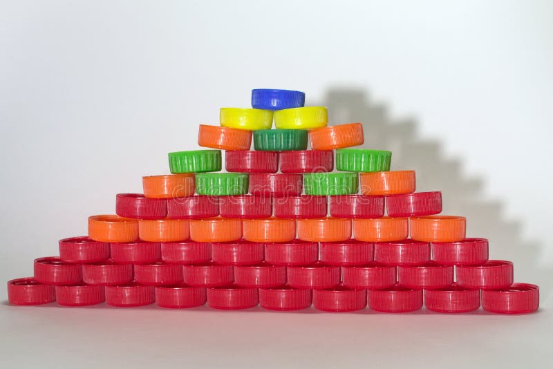 Den plana pyramiden som göras ut ur kulöra plast- kapsyler, gjuter shado arkivfoto Den plana pyramiden som göras ut ur kulöra plast- kapsyler, gjuter shado arkivfoto