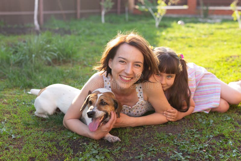 Den positiva unga modern och dottern och hunden ligger på sin hemmabas och får en gemensam vila under royaltyfri fotografi