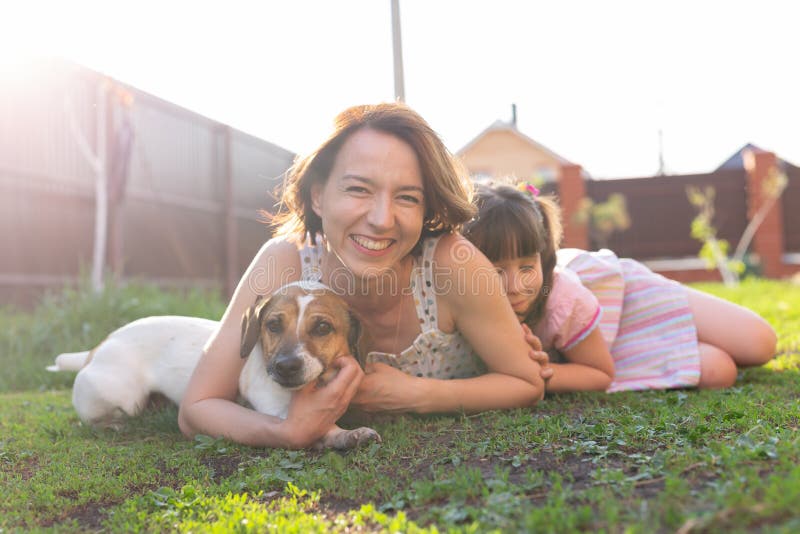 Den positiva unga modern och dottern och hunden ligger på sin hemmabas och får en gemensam vila under royaltyfri foto