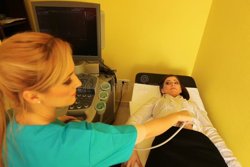 Radiologic technician smiling at mature female patient lying on a CT Scan bed working. Radiologic technician smiling at mature female patient lying on a CT Scan bed working