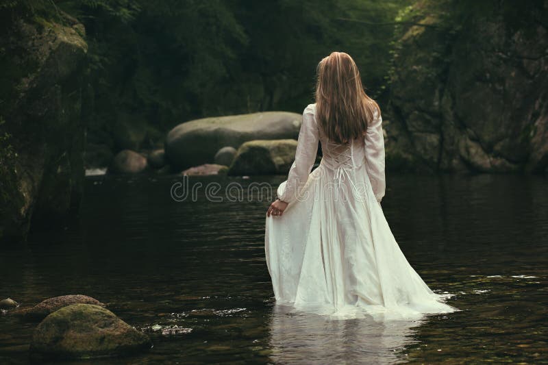 Romantic woman walks into a green stream. Ethereal and dreamy. Romantic woman walks into a green stream. Ethereal and dreamy