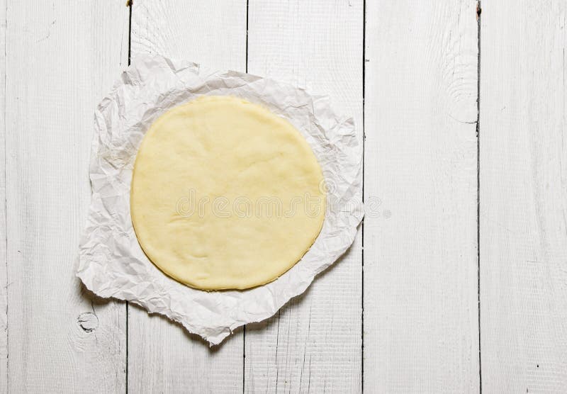 Den rullande ut pizzadegen på papperet arkivbild Den rullande ut pizzadegen på papperet arkivbild