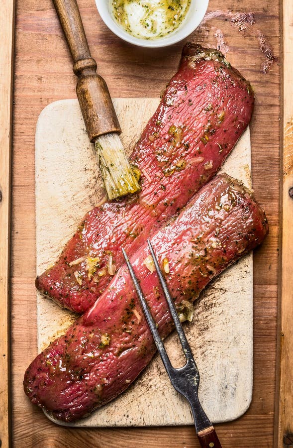 Den rå nya lammfilén som marinerar för att laga mat, eller BBQ-gallret med borsten och kött dela sig, den bästa sikten arkivfoto Den rå nya lammfilén som marinerar för att laga mat, eller BBQ-gallret med borsten och kött dela sig, den bästa sikten arkivfoto