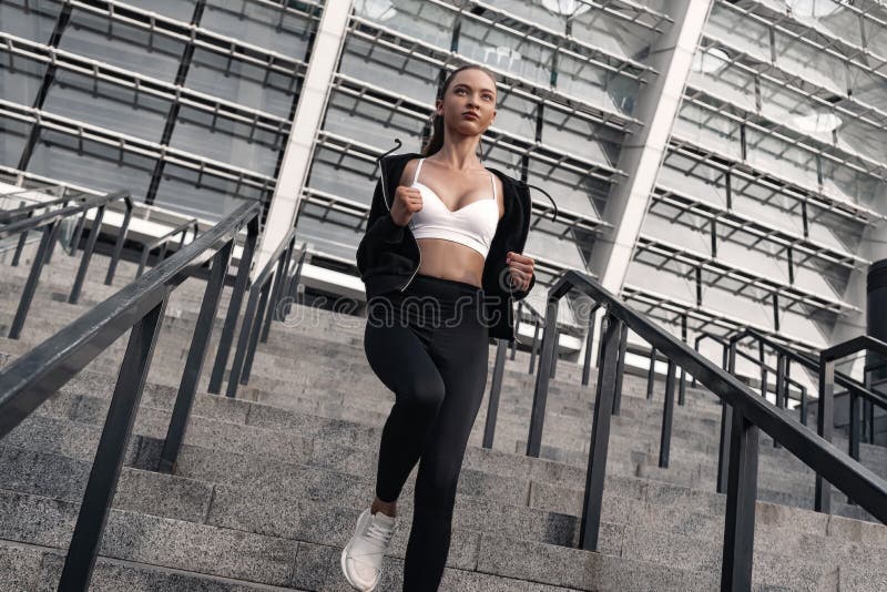 Den sportiga unga kvinnan kör bottenvåning utomhus fotografering för bildbyråer Den sportiga unga kvinnan kör bottenvåning utomhus fotografering för bildbyråer