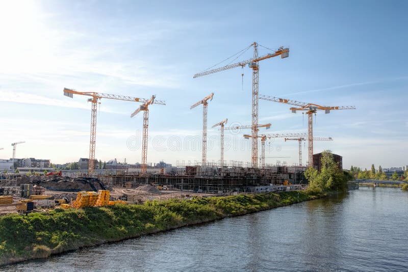 Den stora konstruktionsplatsen med många sträcker på halsen på en flod, på en solig disig dag - Berlin 2018 arkivbild Den stora konstruktionsplatsen med många sträcker på halsen på en flod, på en solig disig dag - Berlin 2018 arkivbild