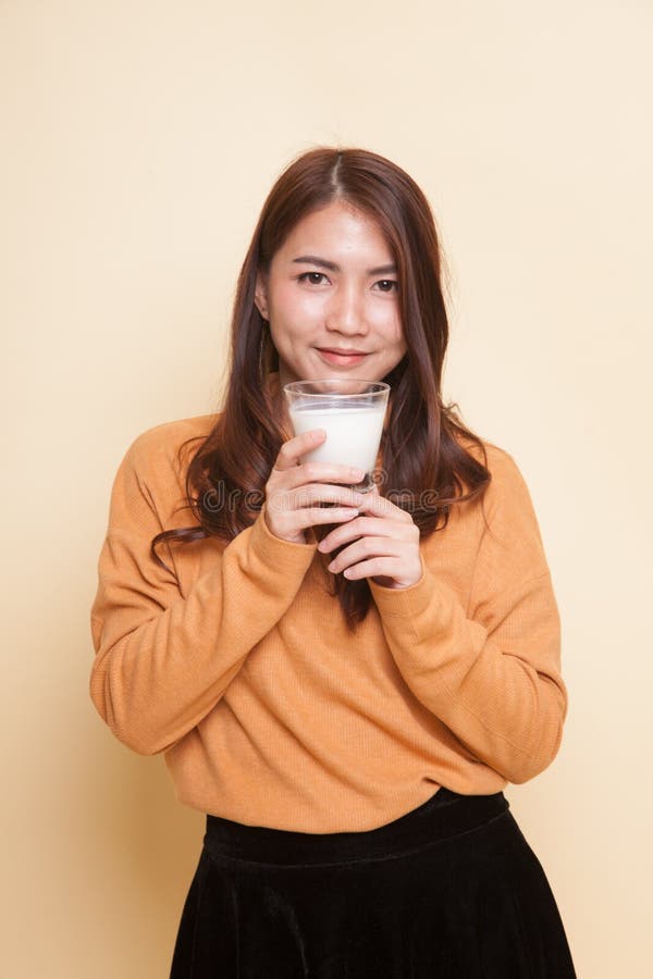 Den sunda asiatiska kvinnan som dricker ett exponeringsglas av, mjölkar