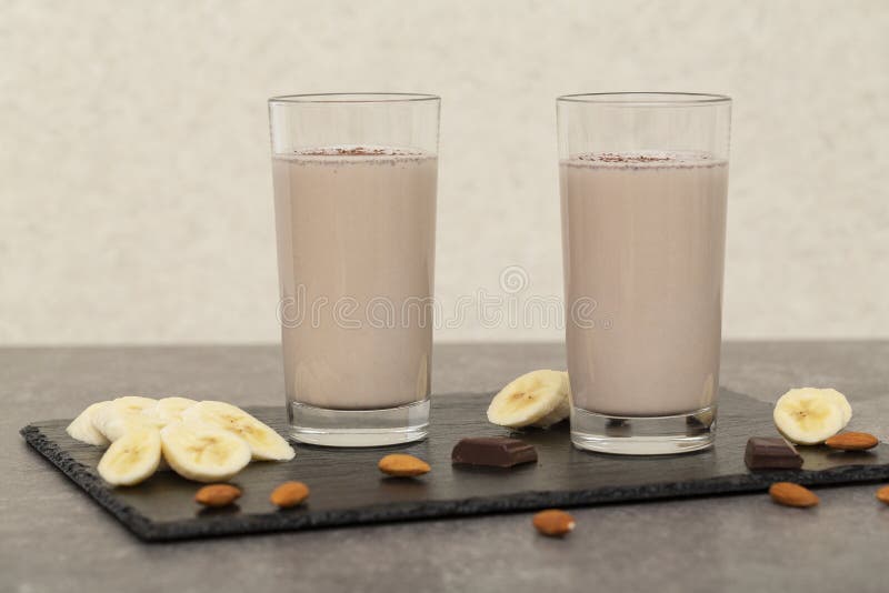 Den sunda chokladproteinskakan med mandeln mj?lkar, bananen, choklad och muttrar sunt smakligt f?r frukost arkivfoto Den sunda chokladproteinskakan med mandeln mj?lkar, bananen, choklad och muttrar sunt smakligt f?r frukost arkivfoto