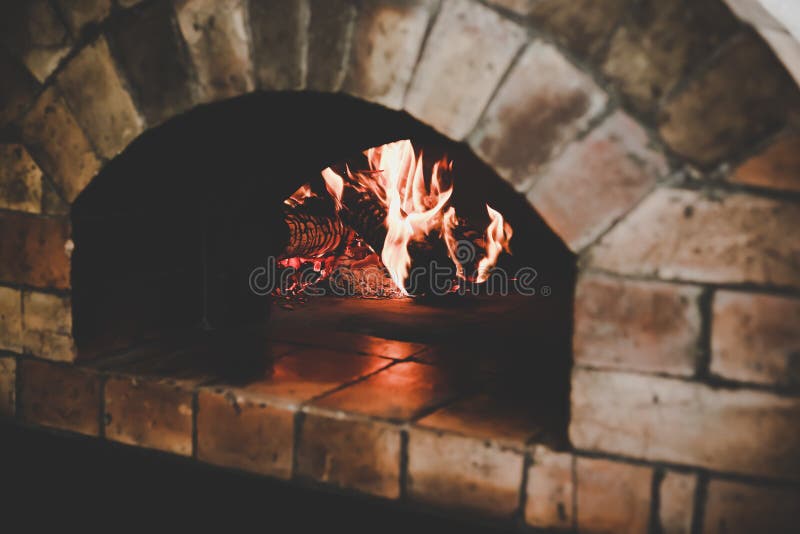 Den traditionella ugnen för tappning gör från bruna tegelstenar med flamman och vedträt för laga mat eller stekhet pizza eller sm royaltyfria bilder Den traditionella ugnen för tappning gör från bruna tegelstenar med flamman och vedträt för laga mat eller stekhet pizza eller sm royaltyfria bilder