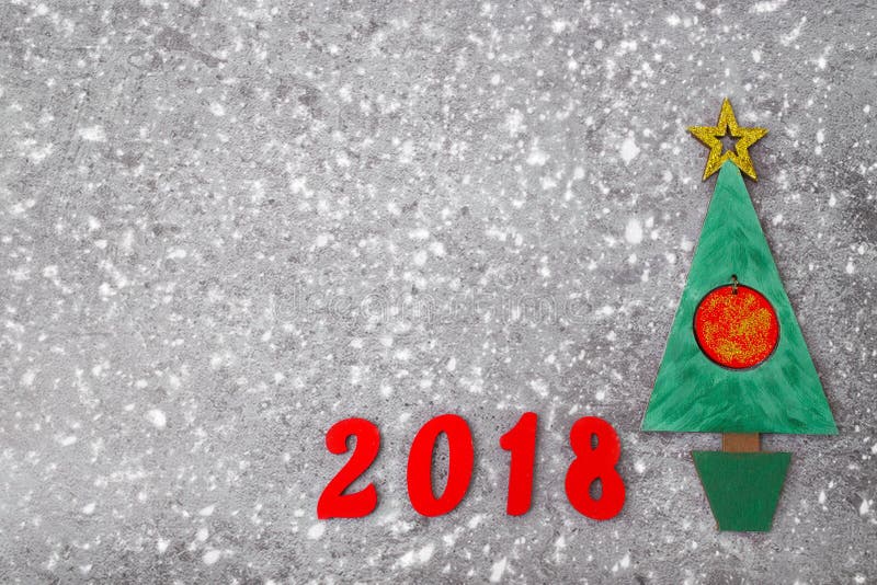 Wooden Green Christmas tree and sign 2018 from wooden red letters, gray concrete background. Happy new year 2018 backdrop. Greeting card. Wooden Green Christmas tree and sign 2018 from wooden red letters, gray concrete background. Happy new year 2018 backdrop. Greeting card.