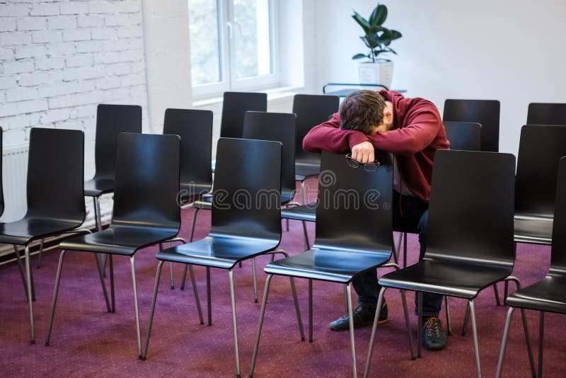 Den trötta unga mannen ta sig en lur i konferensrum royaltyfria foton Den trötta unga mannen ta sig en lur i konferensrum royaltyfria foton