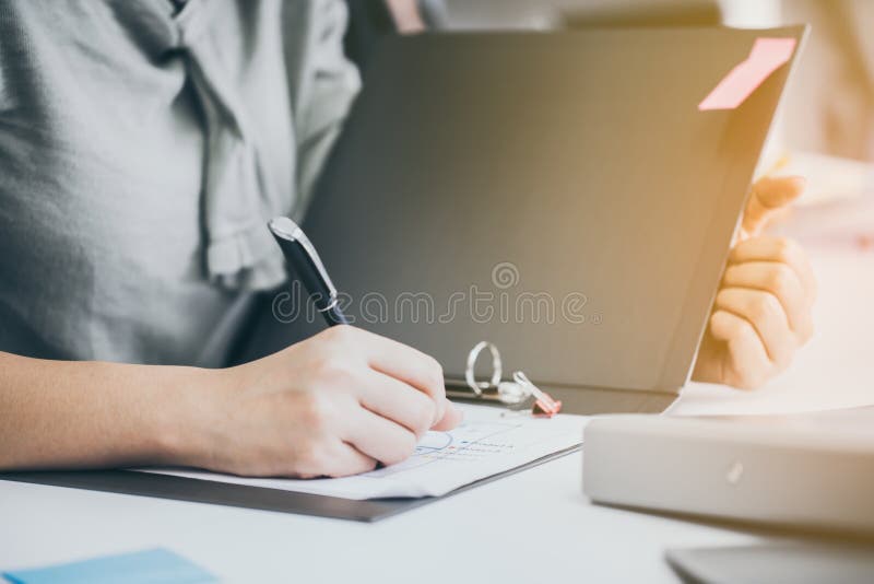 Den unga affärskvinnan undertecknar legitimationshandlingar på en tabell i ett kontor arkivfoto Den unga affärskvinnan undertecknar legitimationshandlingar på en tabell i ett kontor arkivfoto