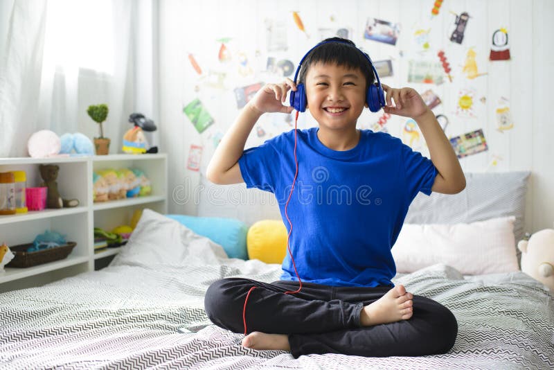 Den unga asiatiska pojken är le och lyssna till musik royaltyfri bild Den unga asiatiska pojken är le och lyssna till musik royaltyfri bild