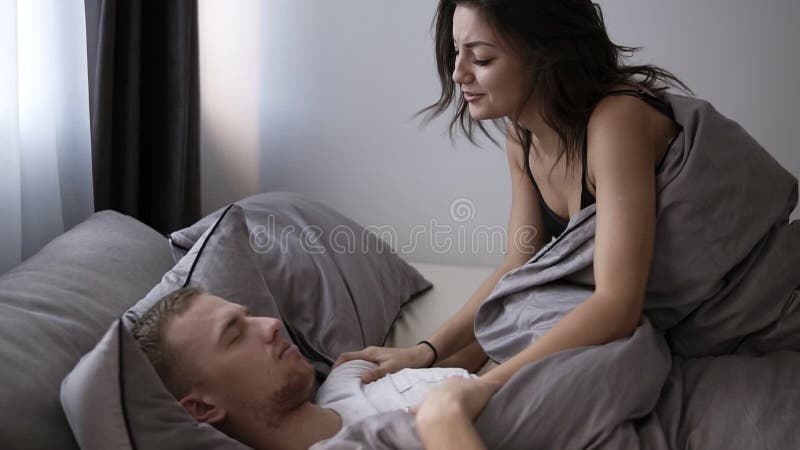 Den unga brunettflickvännen vaknar upp hennes pojkvän eller husbund i morgonen Ha gyckel tillsammans i sängen grått