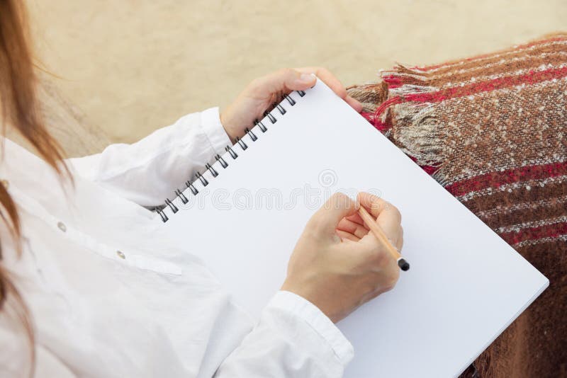 Den unga caucasian kvinnan sitter parkerar in på teckning för bänkhållblyertspenna i sketchbook Rutig brun röd grå pläd Skissa fö fotografering för bildbyråer Den unga caucasian kvinnan sitter parkerar in på teckning för bänkhållblyertspenna i sketchbook Rutig brun röd grå pläd Skissa fö fotografering för bildbyråer