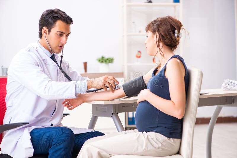Den unga doktorn som kontrollerar gravid kvinnas blodtryck royaltyfri foto Den unga doktorn som kontrollerar gravid kvinnas blodtryck royaltyfri foto